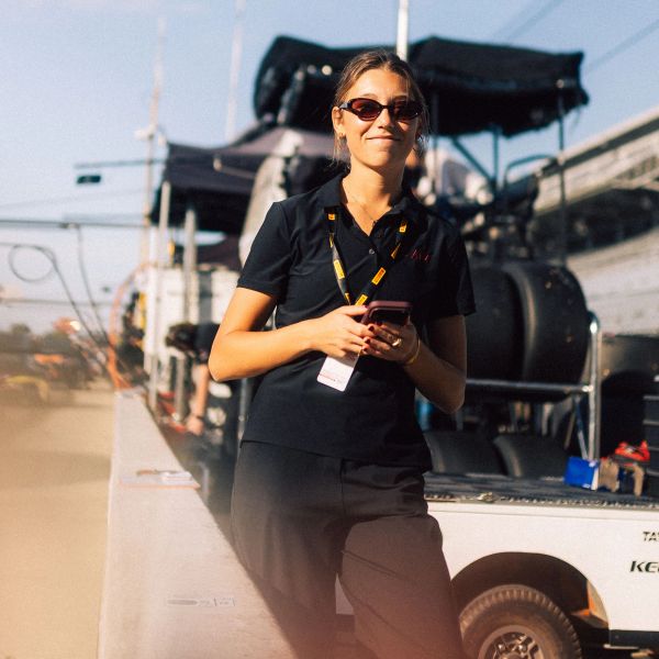 Young woman in sunglasses holding a phone outdoors.