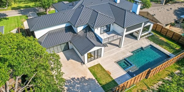 Aerial view of a modern house with a pool and fenced yard.