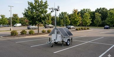 Mobile solar-powered security camera system in parking lot.