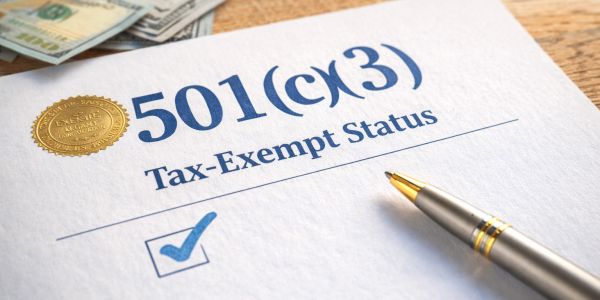 Close-up of a 501(c)(3) tax-exempt status document with a pen and money.