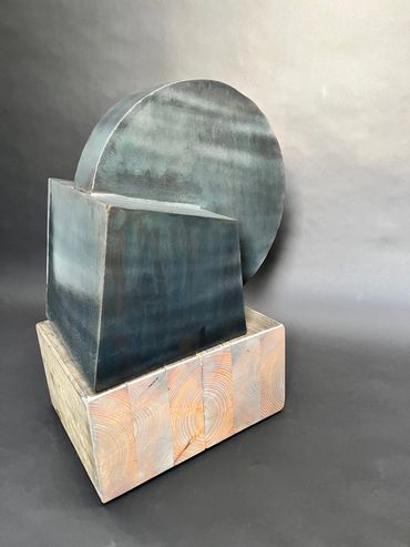 Abstract geometric sculpture with metal and wood elements.