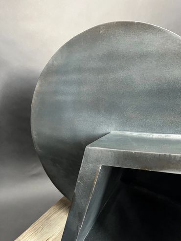 Close-up of a black geometric sculpture with circular and rectangular shapes.