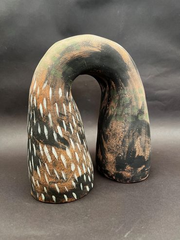 Abstract ceramic sculpture with earthy tones and white markings.