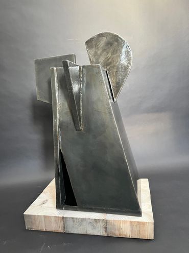Abstract metal sculpture on a wooden base with geometric shapes.