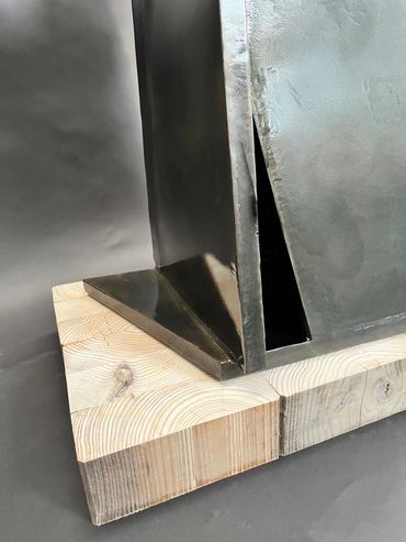 Close-up of black metal structure on wooden blocks.