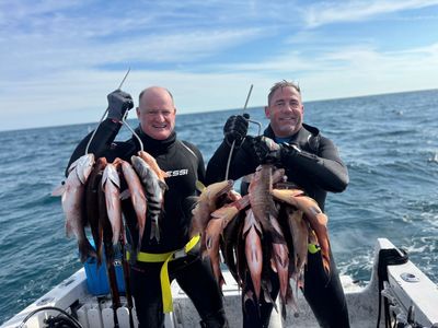 Two men show off their catch while scuba diving.