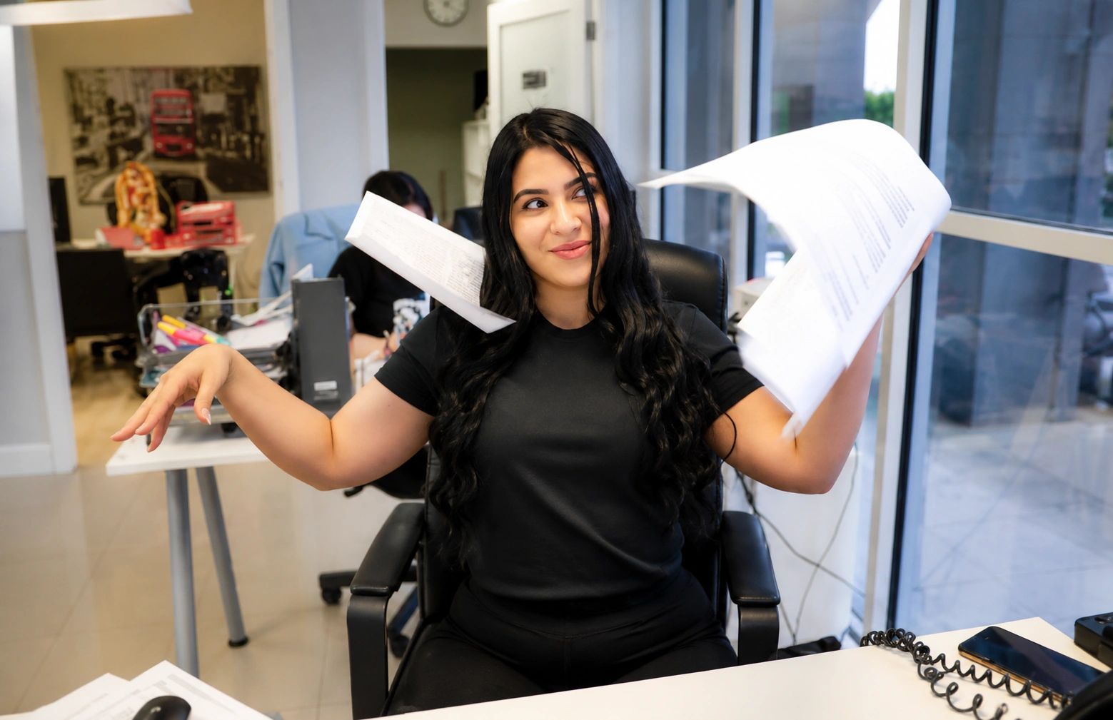 Mujer feliz lanzando papeles en la oficina.