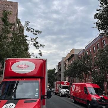 Red delivery vans lined up on a city street under a cloudy sky.