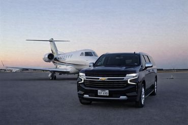 Black Chevrolet SUV parked in front of a private jet on a runway.