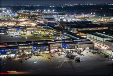 Aerial nighttime view of a busy airport terminal with airplanes and lights.