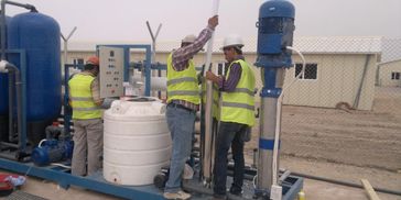 Workers in safety vests inspecting industrial water filtration system.