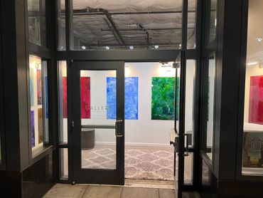 Entrance to a modern art gallery with colorful paintings and a welcoming rug.