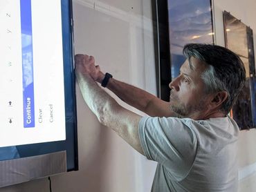 Man fixing or adjusting a wall-mounted flat screen TV.