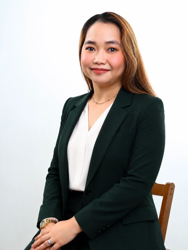 Professional woman in a dark green suit posing confidently.
