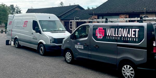 Two vans with WillowJet Exterior Cleaning branding parked in a residential area.