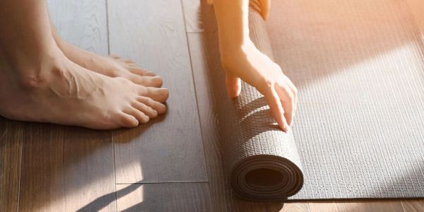 Close-up of feet and hand rolling up a yoga mat.