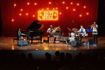 Jazz band performing onstage with piano, guitar, and combo