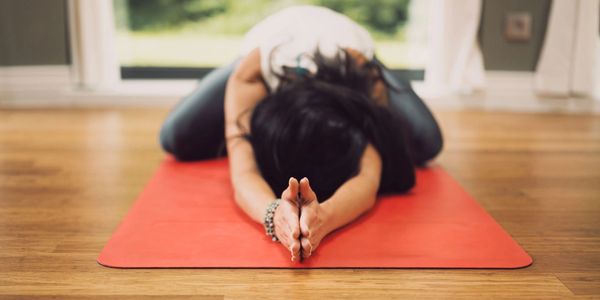 Person stretching on a yoga mat indoors.