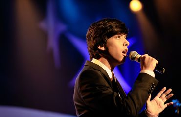 Teenage boy singing a solo with microphone on stage
