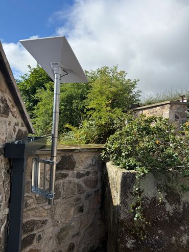 Solar panel mounted on a stone wall under a partly cloudy sky.