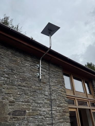 Solar panel mounted on a stone wall under a cloudy sky.