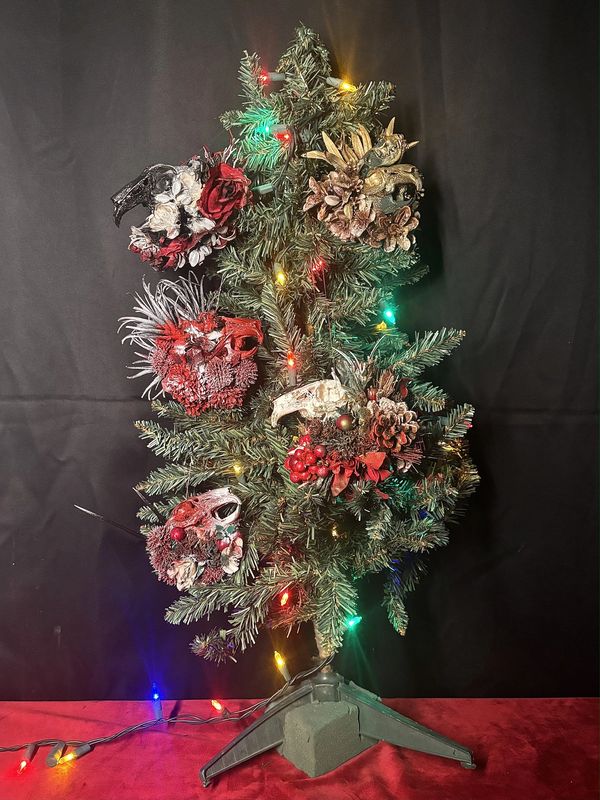 A small Christmas tree decorated with skull and floral ornaments and colorful lights.