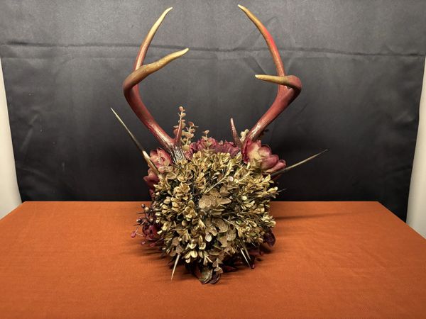 Decorative antlers with golden flowers and spikes on an orange table.