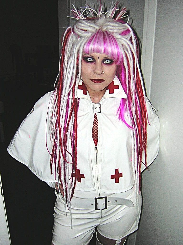Person in a gothic nurse costume with white and pink dreadlocks.