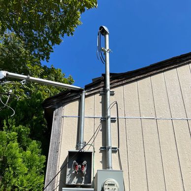Electrical meters and panels mounted on the side of a beige building under a clear blue sky.