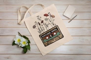 A tote bag with a vintage cassette and flowers design on a wooden surface.