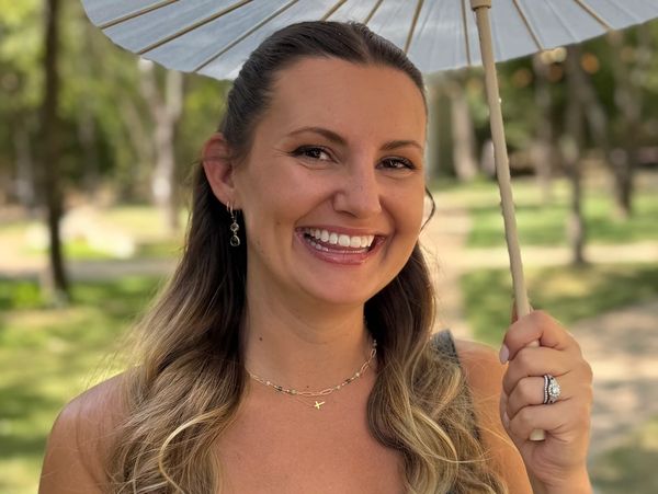 Woman holding a parasol and smiling outdoors.