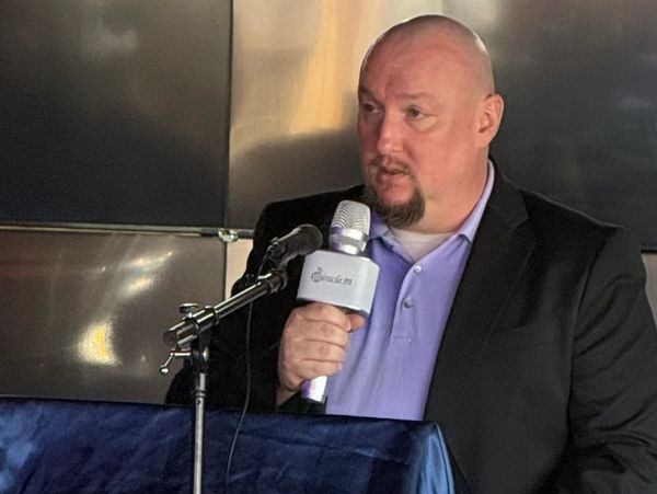 A man speaks into a microphone at a podium during an event.