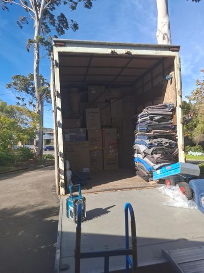 Moving truck loaded with boxes and stacked moving blankets under a clear blue sky.