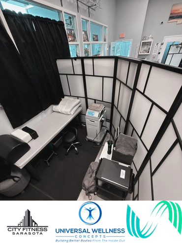 A clean, organized wellness treatment room with a massage table and medical equipment.
