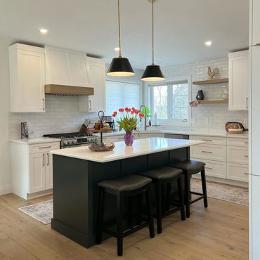 White shaker kitchen with black island and quartz countertops in Grande Prairie renovation.