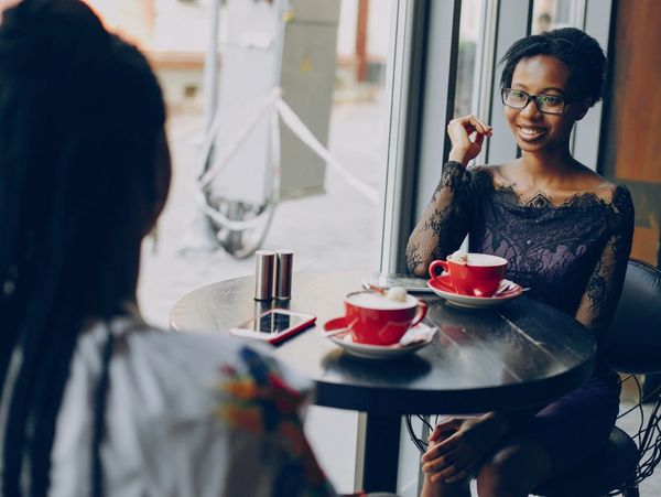 Two women chatting over coffee at a cafe.