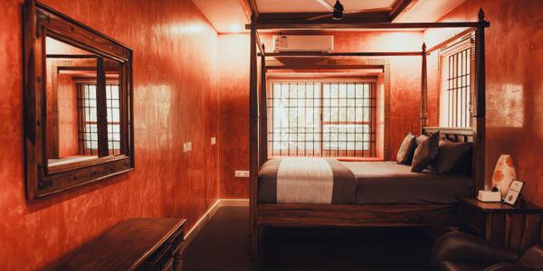 Cozy bedroom with wooden four-poster bed and warm orange walls.