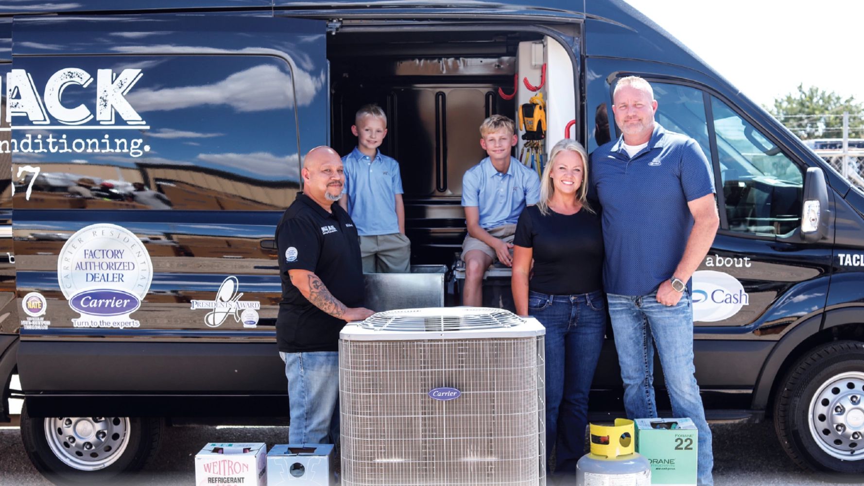 Adults and kids standing next to a service van with an a/c condenser and refrigerant