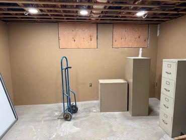 Basement room with a dolly and filing cabinets on a concrete floor.