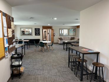 A modern, spacious room with tables, chairs, and a cozy sitting area.