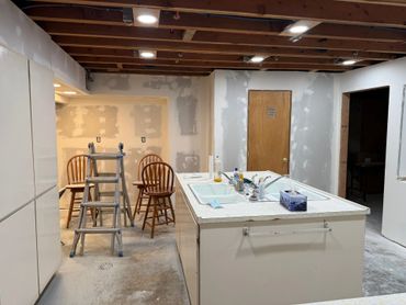 Unfinished basement kitchen with exposed ceiling and ladder.