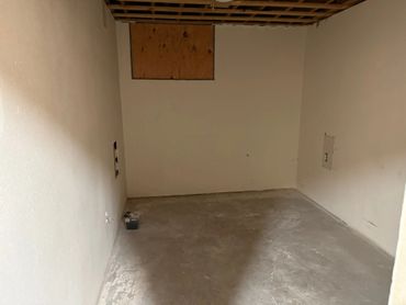 An empty unfinished basement room with bare walls and concrete floor.