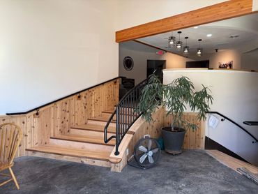 Wooden stairs with black railings and a potted plant in a cozy interior.
