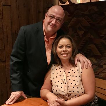 Couple posing and smiling at a table.
