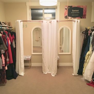 Dressing room with three fitting areas and hanging clothes.