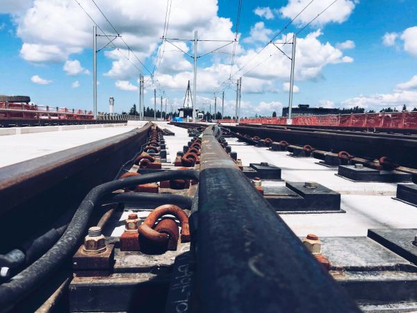 Close-up view of railway tracks under a bright blue sky with clouds.