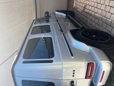 Silver Mercedes-Benz G63 parked under a shade with black wheels.