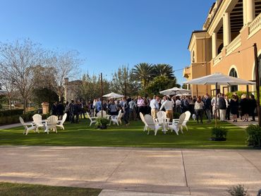 Outdoor business networking event with people mingling on a sunny day.