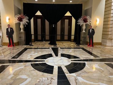Elegant event entrance with marble floor and tuxedo cutouts.