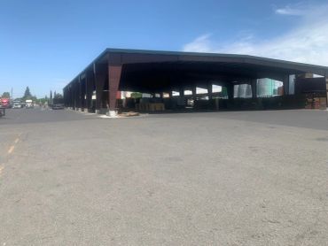 Large industrial shed with trucks nearby on a clear day.